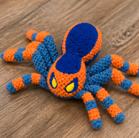 Crocheted spider toy with blue and orange colors on a wooden surface