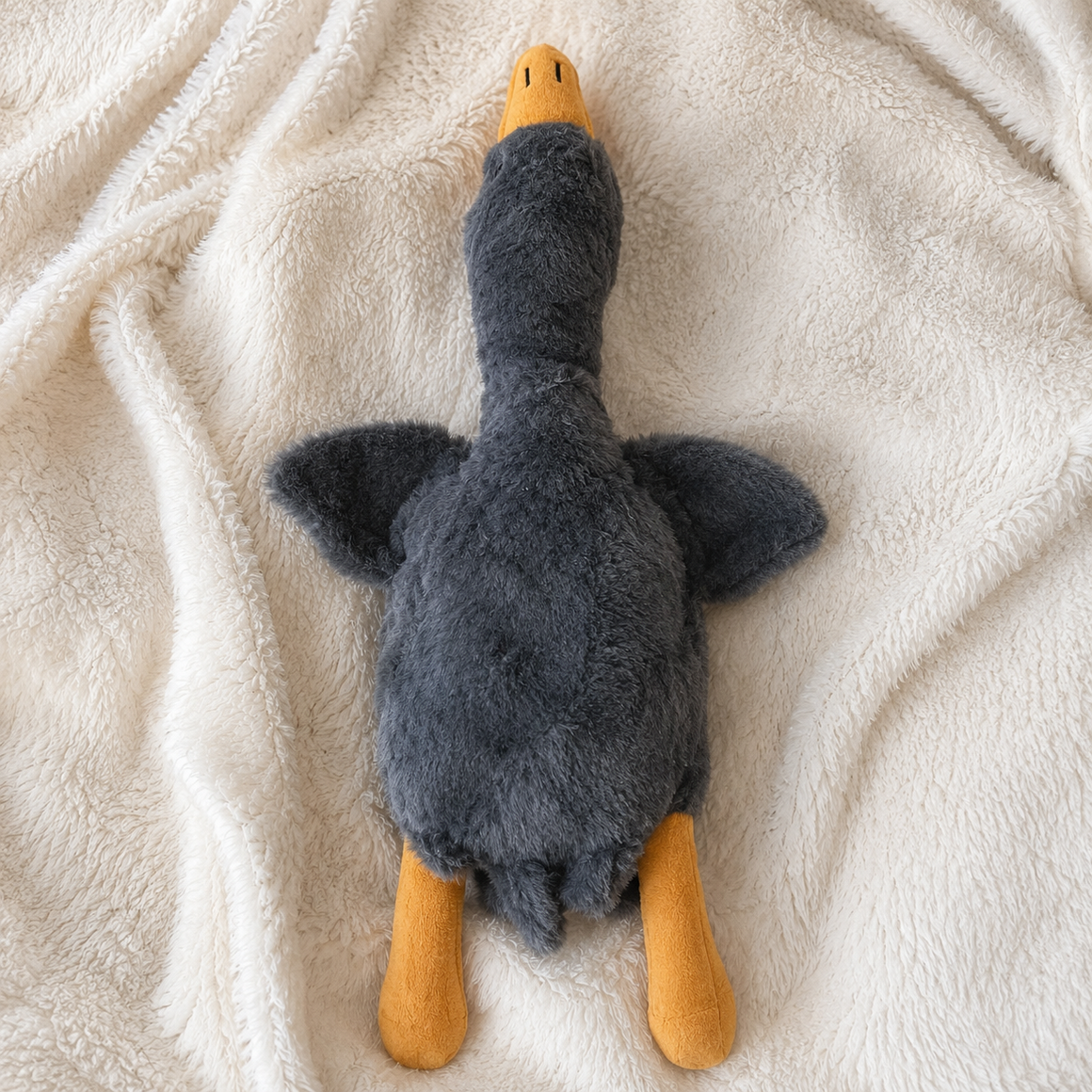 Plush toy resembling a duck on a soft beige surface