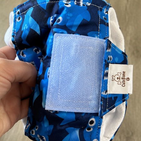 Blue patterned diaper with a visible brand label on a wooden floor.