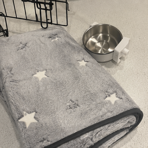 Gray blanket with star patterns on a surface next to a metal bowl.